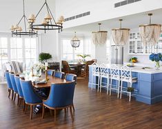 a large kitchen with blue chairs and white counter tops in front of a dining room table