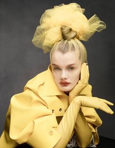 a woman with yellow hair and gloves on her head, wearing a yellow outfit that has sheer tulle over it