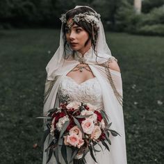 a woman in a wedding dress holding a bouquet and wearing a veil on her head