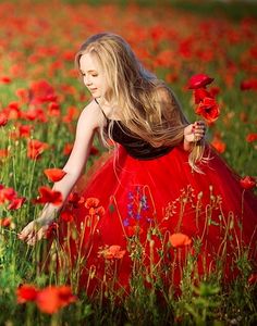 a woman in a red dress standing in a field of flowers