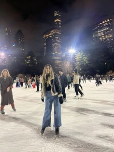 people skating on an ice rink at night in front of the city lights and skyscrapers