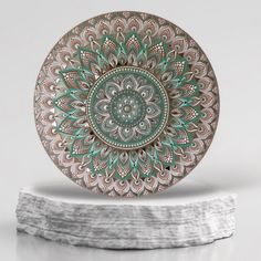 a green and white plate sitting on top of a piece of driftwood with an intricate design