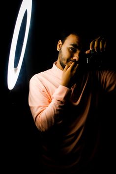 a man holding a camera up to his face in front of a light that is shining on him