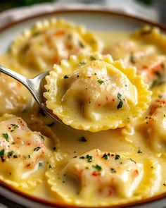 a spoon full of ravioli with shrimp and parmesan cheese in a white bowl