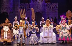 a group of people standing on top of a stage next to each other wearing costumes