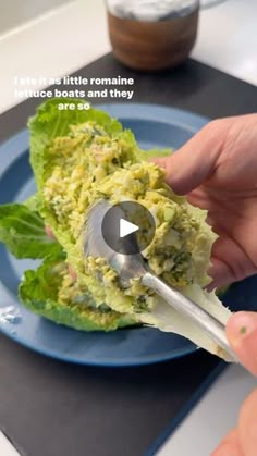 a person is holding a spoon over some food on a plate with lettuce