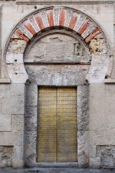 an old building with two gold doors and a brick arch over the entrance to it