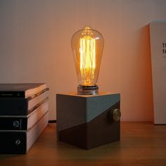 a light bulb sitting on top of a wooden block next to books and a lamp