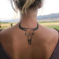 a woman with a bull's head tattoo on her upper back neck is looking at the camera