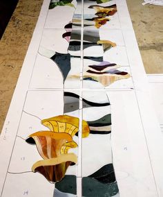 several pieces of stained glass are laid out on the floor to be painted with different colors