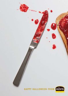 a piece of bread with ketchup on it next to a knife that has been cut in half