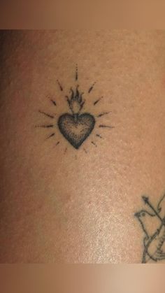 a small tattoo on the back of a woman's stomach with a bird and heart