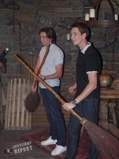 two young men are holding brooms and cleaning the floor