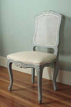 a white chair sitting on top of a hard wood floor next to a blue wall