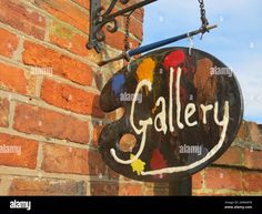 an old sign hanging from the side of a brick building that says gallery - stock image