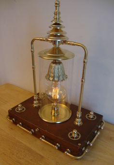 an old fashioned lamp is sitting on top of a wooden table with brass fittings