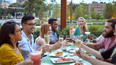 a group of people sitting around a table with food and drinks