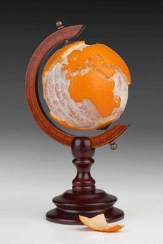 an orange is sitting on top of a wooden stand with the earth in it's center