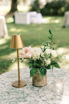 a table topped with a vase filled with flowers next to a lamp on top of a table