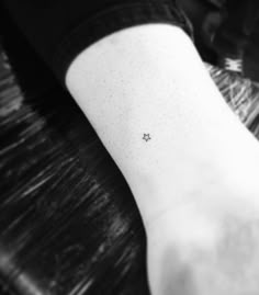 a person's foot with a tiny star tattoo on their left ankle and the word,