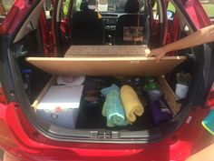 the back end of a red car filled with items