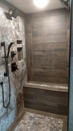 a walk in shower sitting next to a tiled floor and wall with wooden paneling