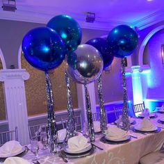 a table with blue balloons and silver plates on it