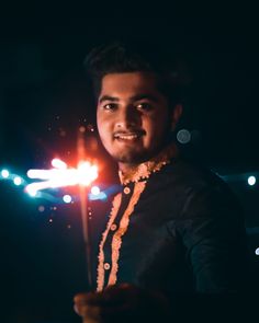 a man holding a sparkler in the dark