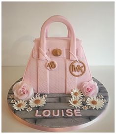 a cake that is shaped like a purse and has flowers on the bottom, along with daisies