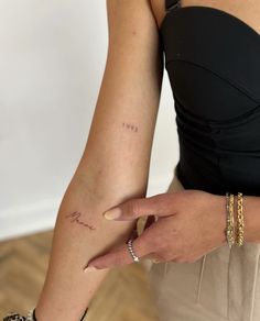 a woman's arm with the word love tattooed on her left hand and two gold bracelets