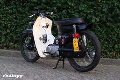 a white and black motorcycle parked next to a bush