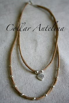 two necklaces on a white cloth with the words collar anteloba written above them