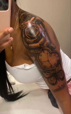 a woman taking a selfie with her cell phone and clock tattoo on her arm