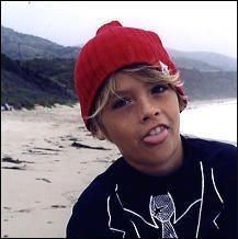 a young boy wearing a red hat on the beach