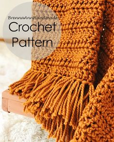 an orange crochet blanket sitting on top of a white rug next to a wooden frame