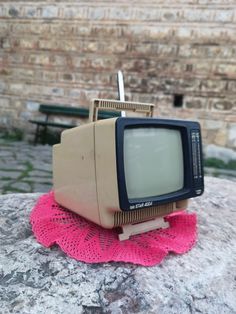 an old tv sitting on top of a rock