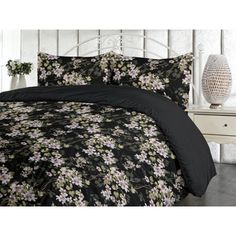 a bed with black and white floral comforter set on it's headboard