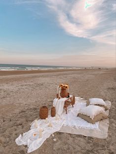 an owl statue sitting on top of a blanket at the beach next to some candles