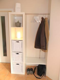 a white shelf with baskets and shoes on it next to a wall mounted coat rack