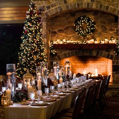 a long table is set with candles and place settings for an elegant christmas dinner in front of the fireplace