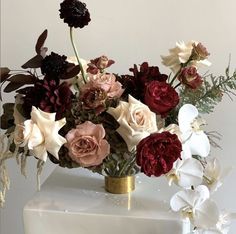 a vase filled with lots of flowers on top of a white tablecloth covered cake