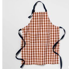 an orange and white checkered apron hanging on a wall