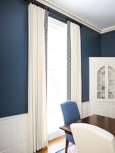 a blue and white dining room with a table, chair, and china cabinet in the corner