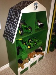 there is a green shelf with toy cars on it and a cat laying in the bottom one