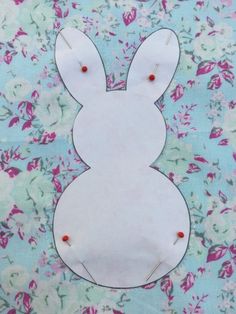 a paper cut out of a bunny sitting on top of a flowery table cloth