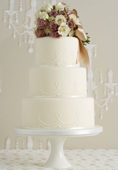 the wedding cake is decorated with white and pink flowers, while the bride and groom are standing next to each other