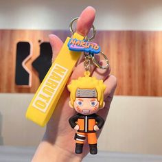 a hand holding a keychain that has a cartoon character on the front and back