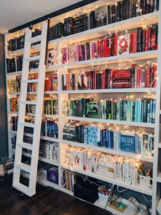 a bookshelf filled with lots of books next to a wall covered in lights