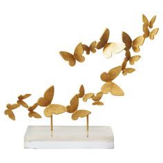 gold butterflies are flying in the air on top of a white stand with wooden sticks