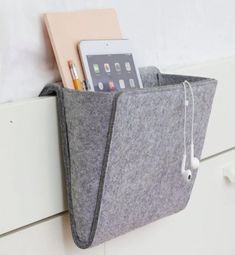 an ipad and earbuds in a felt pocket on a white cabinet door handle